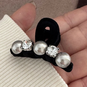Macro detail of a mini black velvet hair claw clip with pearls and rhinestones decoration
