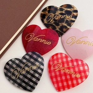 Close-up of assorted heart hair clips in leopard, glitter, and plaid with Vannie logo