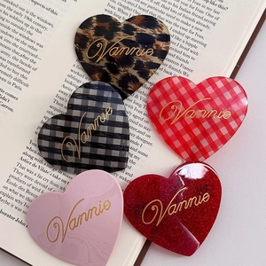 Close-up of heart-shaped acetate hair clips in five colors resting on a vintage book