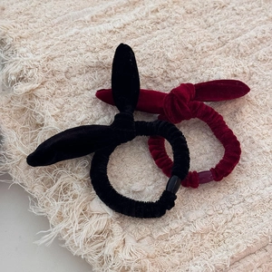 Vue détaillée de chouchous oreilles de lapin en velours noir et bordeaux sur tissu
