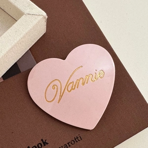 Close-up of pink heart-shaped acetate hair clip with gold Vannie lettering detail