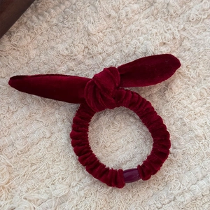 Gros plan du chouchou en velours bordeaux avec oreilles de lapin sur fond blanc doux