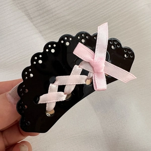 Dettaglio di una clip per capelli Lolita nera in resina con nastro rosa e fiocco