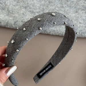 Detailed shot of handmade grey fabric headband with crystal beads and 'HAND MADE' label