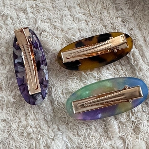 Detailed close-up of acetate duckbill clips with marble patterns and gold metal mechanism