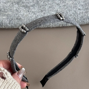 Detailed view of the gray knitted headband featuring sparkling silver diamond bead accents