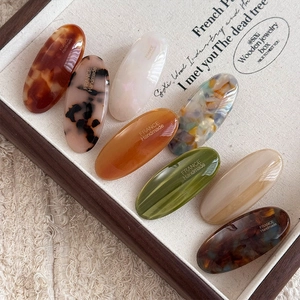 Detail view of oval acetate hair clips in assorted marble and tortoiseshell patterns