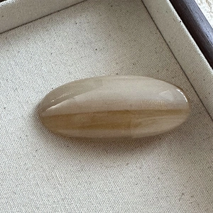 Detail of light brown acetic acid hair clip with engraved hand made gold logo text