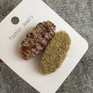 Detailansicht von Tweed und olivgrünen Plüsch-Haarspangen auf einer Display-Karte