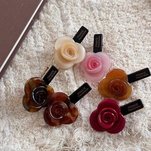 Elegant set of six French acetate rose hair clips in various colors on a plush background