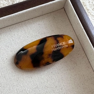 Detailed macro view of acetate hair clip showing tortoise shell pattern and handmade text