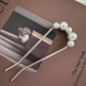 Close-up of U-shaped hair pin with five gradient pearls on silver metal base