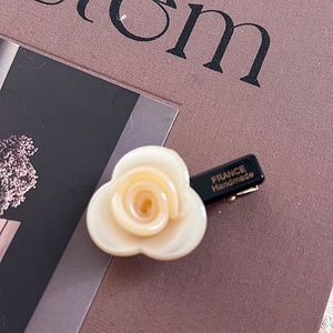Close-up of elegant ivory resin rose hair clip with gold France Handmade lettering