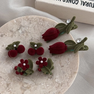 Detailed set of red flocked cherry, tulip, and flower hair clips on a marble tray