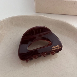 Détail de la pince à cheveux en acétate marron avec logo doré France Handmade