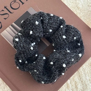 Dettaglio di un elastico per capelli nero a pois in tessuto boucle su sfondo morbido