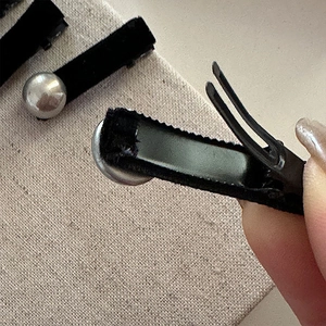 Macro detail of black velvet hair clip with silver ball and metal spring mechanism