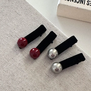 Detail of four velvet hair clips with red wine and silver decorative pearls on fabric
