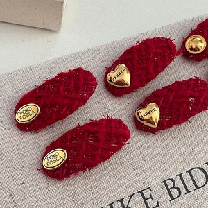 Detailed close-up of red tweed hair clips with golden heart and oval metal accents