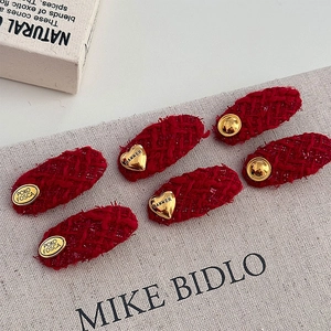 Detailed view of red tweed hair clips with gold heart and round embossed metal accents
