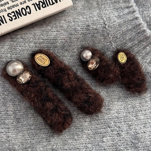 Brown fuzzy hair clips set with pearls and crystals on soft grey knitted background