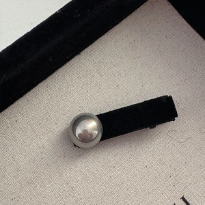 Detailed macro view of a silver pearl hair clip on a black velvet display stand