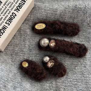 Set of four vintage brown plush hair clips with gold tags and pearls on knit fabric