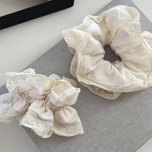 Detailed view of cream lace scrunchies with floral embroidery and textured fabric