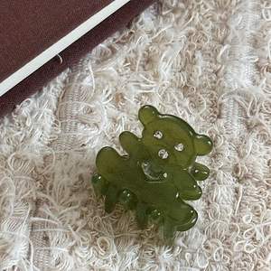 Détail macro d'une mini pince à cheveux ours en résine translucide vert armée