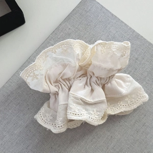 Close-up of vintage creamy white lace hair scrunchie with intricate floral embroidery details