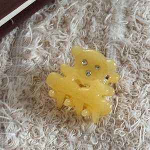 Détail d'une pince à cheveux ours en résine jaune avec strass sur fausse fourrure