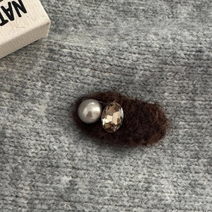 Close-up of a vintage brown fuzzy hair clip with an elegant pearl and faceted rhinestone
