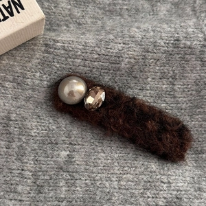 Detail of plush brown hair clip with a grey pearl and faceted brown rhinestone