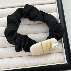 Dettaglio dell'elastico in raso nero pieghettato con resina ambrata e perla elegante