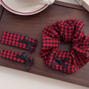 Retro red houndstooth hair clip set with scrunchie and bow detail on a wooden tray