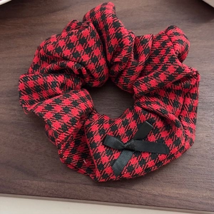Detailed view of vintage red houndstooth hair scrunchie with a black silk bow decoration