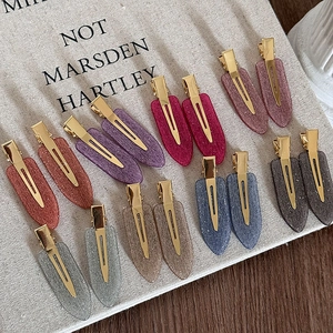 Détail de barrettes à paillettes en forme de goutte avec pince crocodile dorée