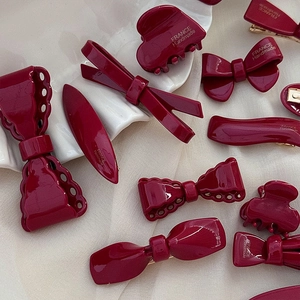 Détails des pinces à cheveux bordeaux vintage sur un plateau en céramique blanc