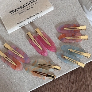 Minimalist marble pattern acetate hair clips with gold metal base on beige fabric