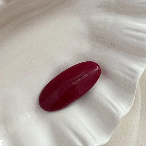 Détail d'une pince à cheveux ovale bordeaux avec texte France Handmade gravé