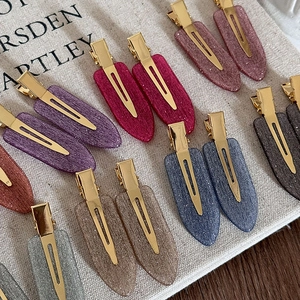 Pinces à cheveux pailletées aux couleurs Morandi avec clips dorés sur fond de lin