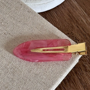 Detailed macro view of pink marble texture resin hair clip with elegant golden metal base