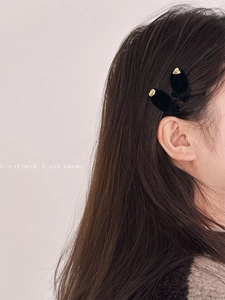 Minimalist black velvet hair clips with gold heart accents on a female model