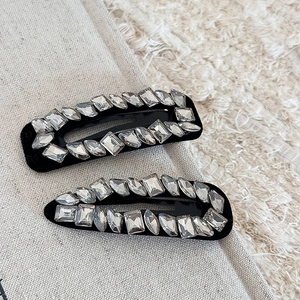 Close-up of luxury water drop hair clips with sparkling rhinestones on black base