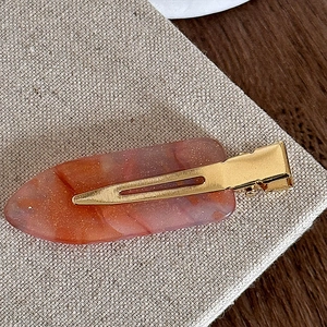Macro view of a marble texture acetate hair clip with gold glitter and metal clasp