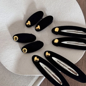 Vintage black velvet hair clips set with gold heart accents on a grey display tray
