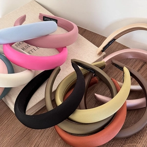 Detail showing various colors of thick sponge headbands with handmade labels on wood surface