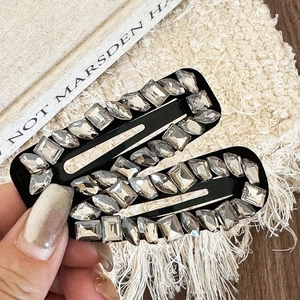 Elegant two-piece set of black alloy hair clips with grey sparkling rhinestones on hand