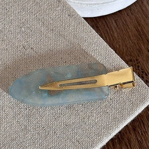 Macro detail of a blue translucent resin hair clip with fine glitter and gold metal base
