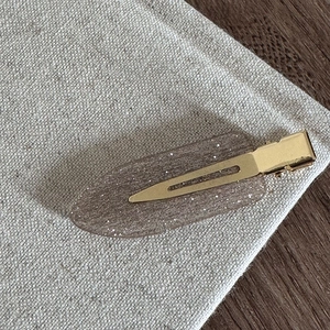 Détail d'une pince à cheveux élégante en résine avec base dorée et finition pailletée